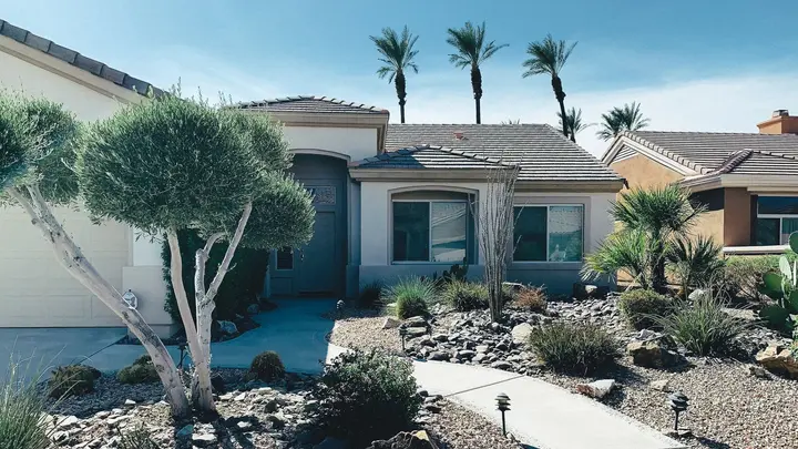 A single-story Arizona home with desert landscaping and palm trees