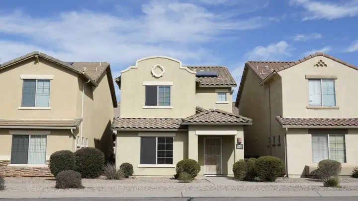 A row of newer stucco homes with tile roofs in an Arizona subdivision